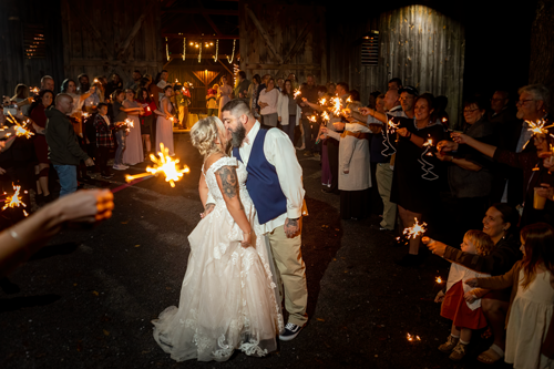 Couple standing outside the barn at Standing Stone Estates kissing with a sparkler sendoff